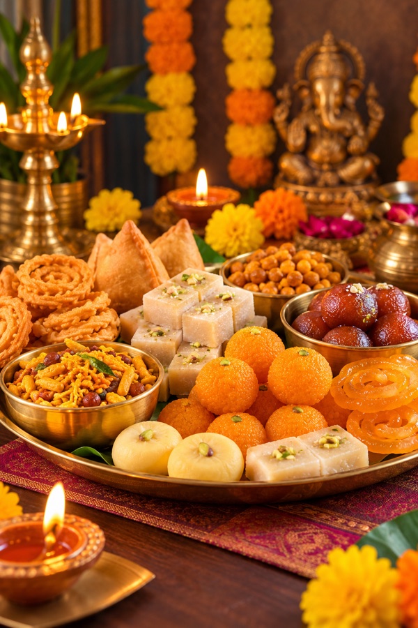 Festive thali of Indian sweets and savouries with diyas and marigolds
